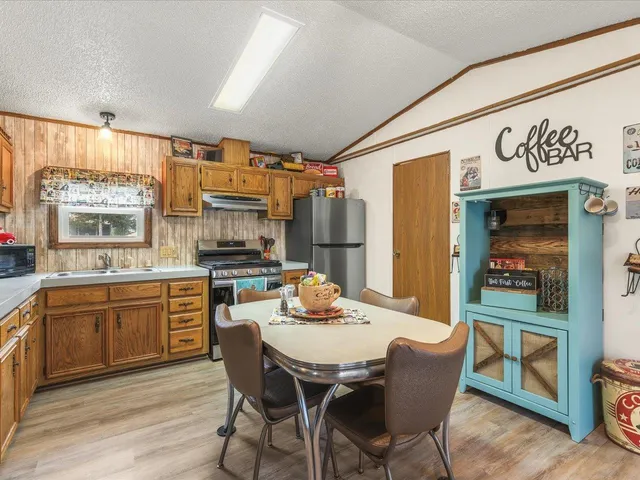 a kitchen with stainless steel appliances granite countertop a kitchen island hardwood floor sink stove dining table and chairs