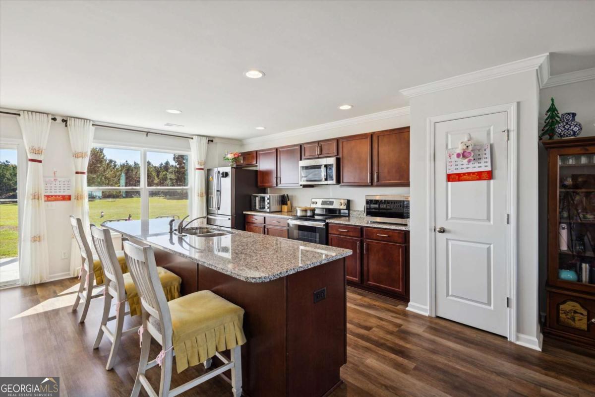 455 Tondee Way Midway, GA 31320 - Photo 9 of 52 a kitchen with stainless steel appliances granite countertop a stove a refrigerator a kitchen island a table and chairs