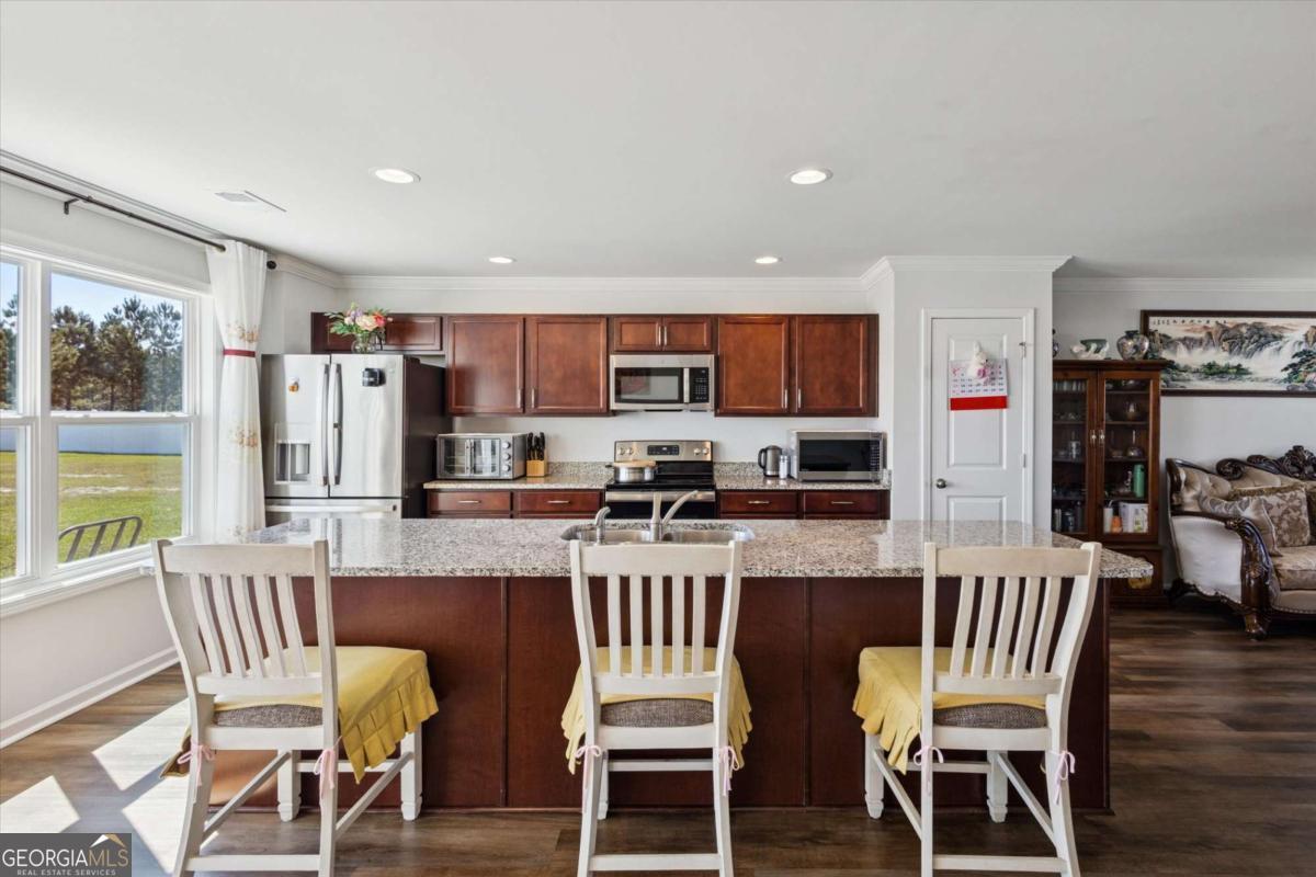 455 Tondee Way Midway, GA 31320 - Photo 10 of 52 a kitchen with stainless steel appliances granite countertop a dining table chairs refrigerator and microwave
