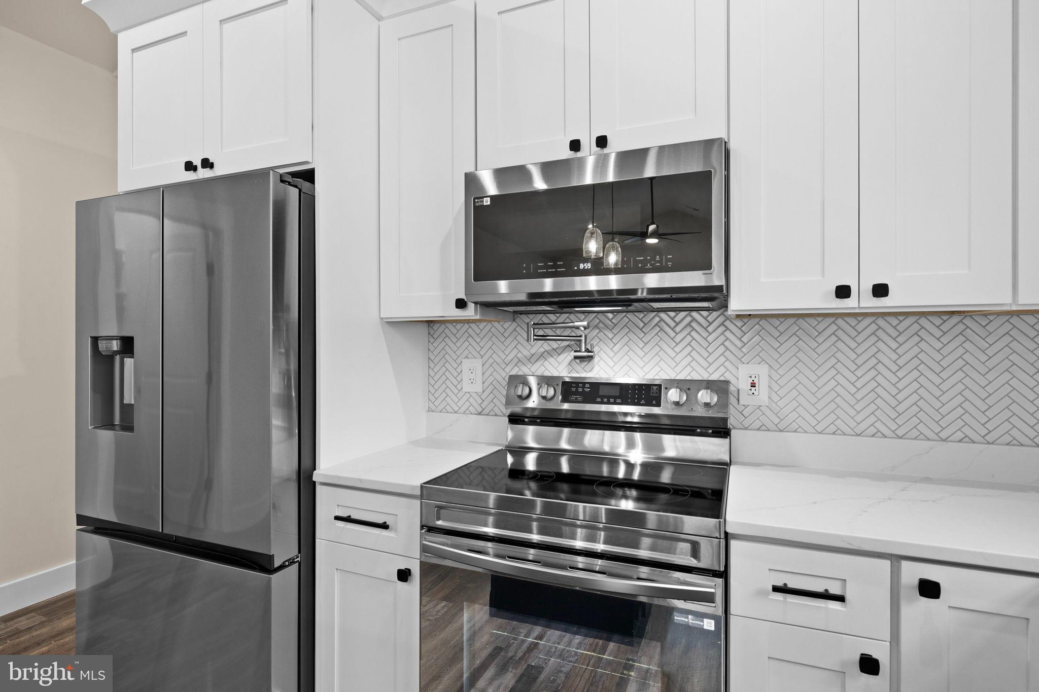 312 9th Street Colonial Beach, VA 22443 - Photo 9 of 59 a kitchen with stainless steel appliances white cabinets and a stove