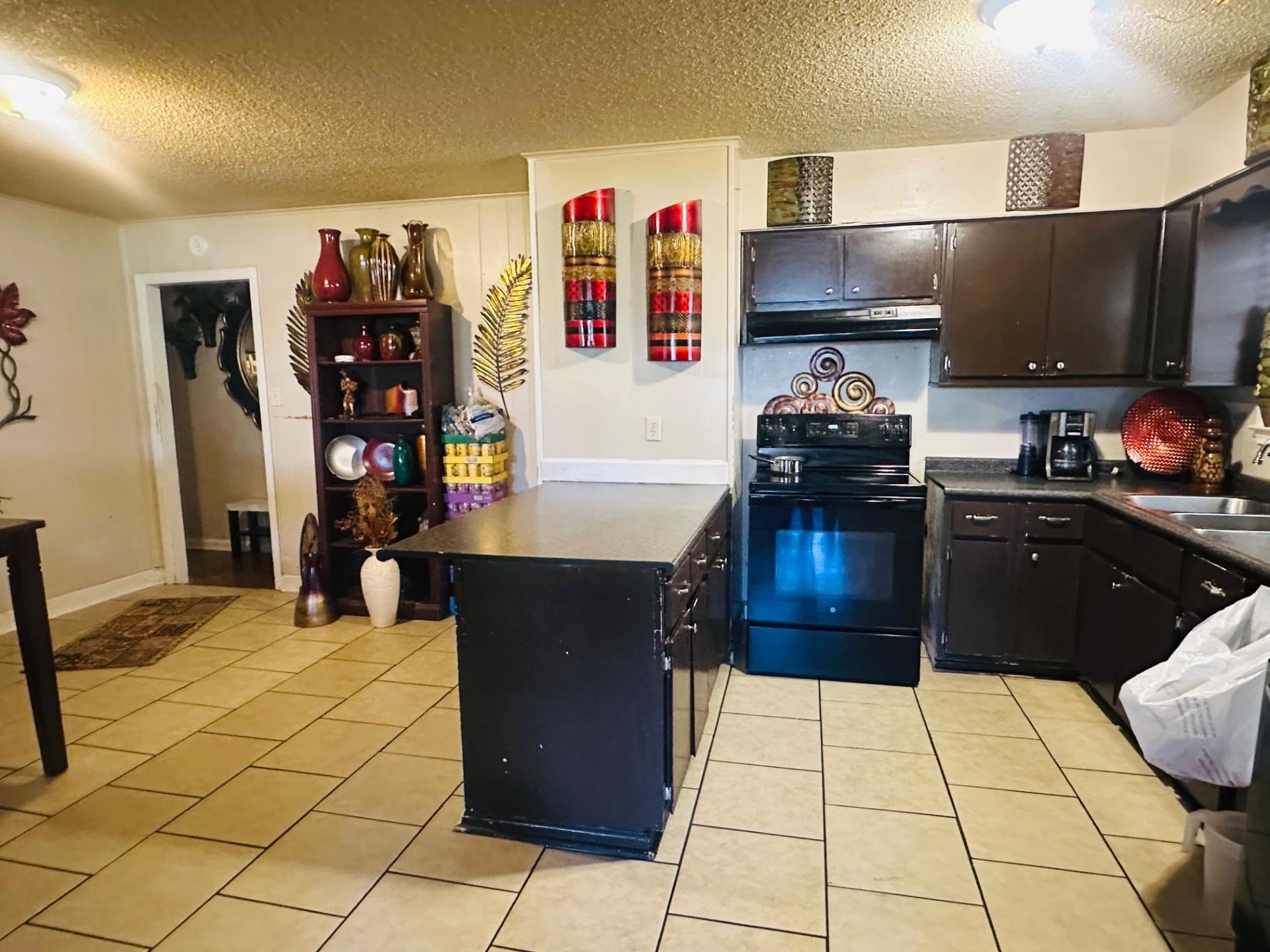 4775 Stacey Road Memphis, TN 38109 - Photo 7 of 13 Kitchen with dark countertops, a textured ceiling, black / electric stove, light tile patterned floors, and a peninsula