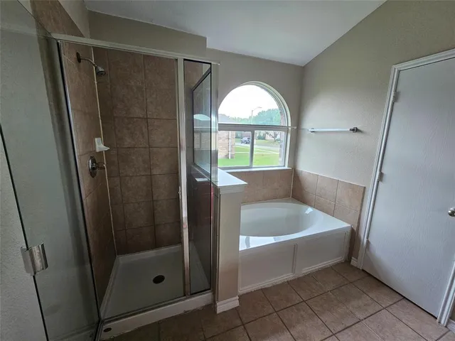 a bathroom with a tub a mirror and a shower