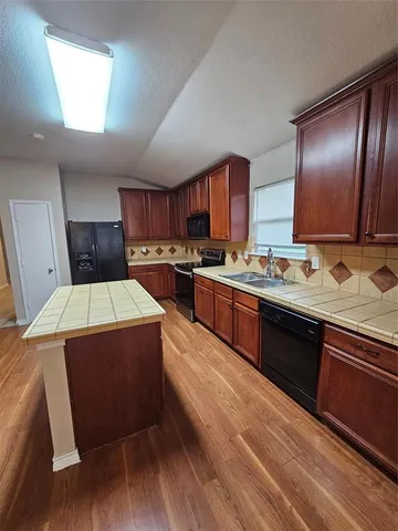 a kitchen with stainless steel appliances granite countertop wooden cabinets a stove a sink and a refrigerator