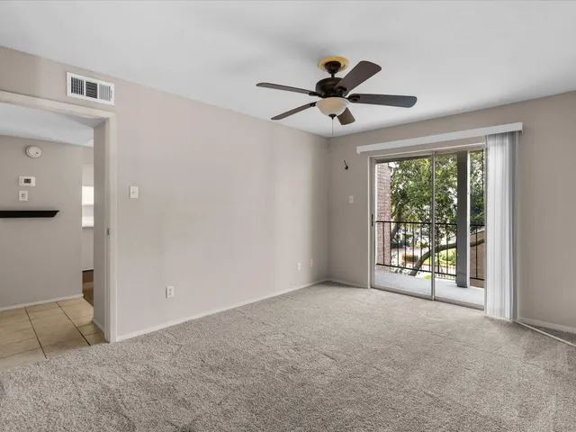 an empty room with ceiling fan and windows