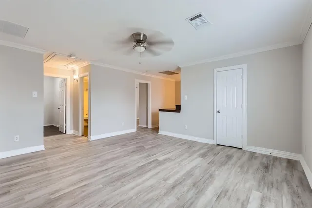 an empty room with wooden floor ceiling fan and windows