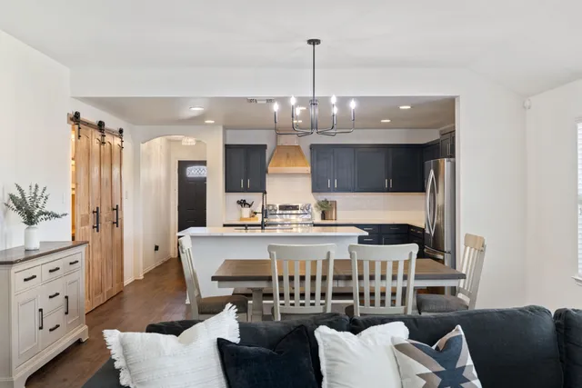 a view of kitchen with stainless steel appliances kitchen island granite countertop dining table and chairs