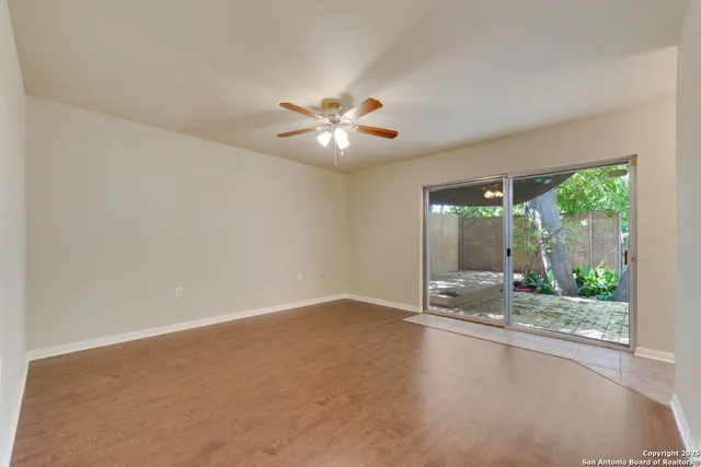 an empty room with large windows and a ceiling fan