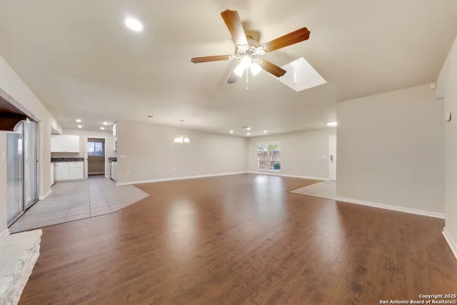 a view of an empty room with wooden floor and a ceiling fan