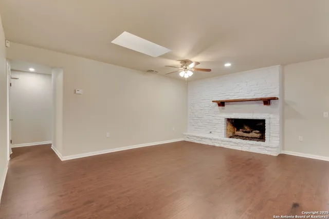 an empty room with a fireplace and chandelier fan