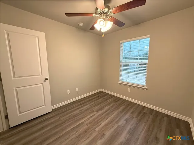 an empty room with windows and fan