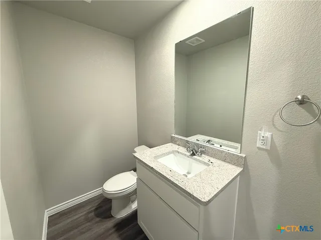 a bathroom with a granite countertop toilet and a sink