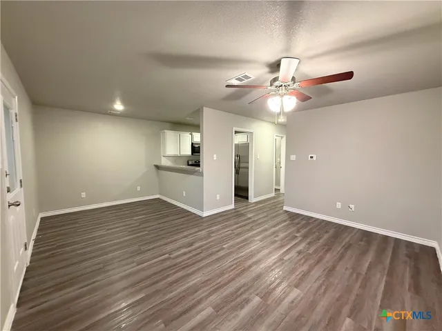 a view of an empty room with window and wooden floor