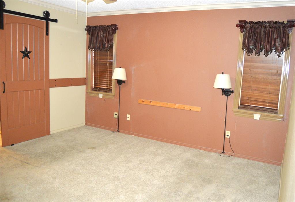 1012 Meridith Drive Terrell, TX 75160 - Photo 23 of 26 Primary bedroom featuring light colored carpet, crown molding, a barn door, and a ceiling fan