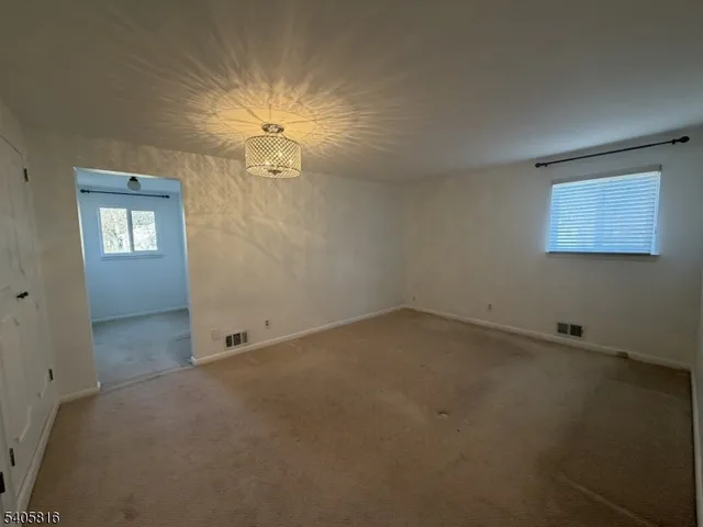 an empty room with a fan & a window