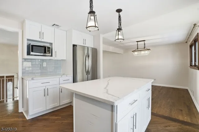 a kitchen that has a refrigerator a stove and white cabinets with wooden floor