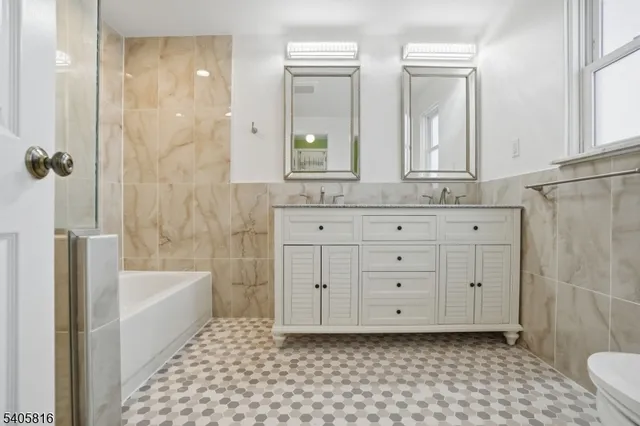 a bathroom with a granite countertop sink a toilet a mirror and shower