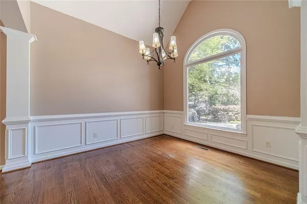 a view of an empty room with a window and wooden floor