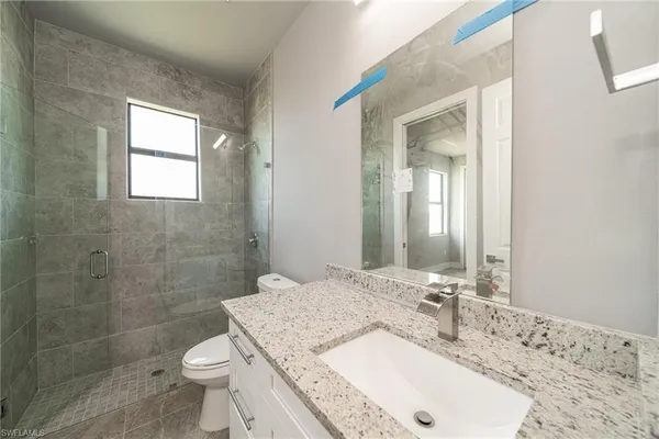 a bathroom with a granite countertop sink a toilet and shower