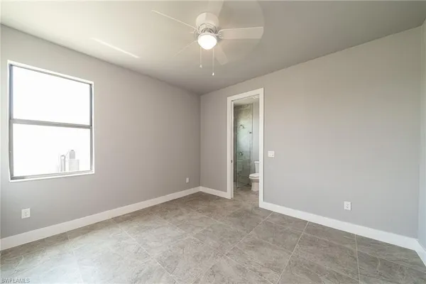 an empty room with chandelier fan and windows