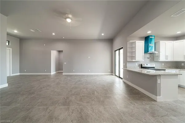 a large hall with stainless steel appliances granite countertop a sink and cabinets