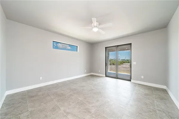an empty room with windows and ceiling fan