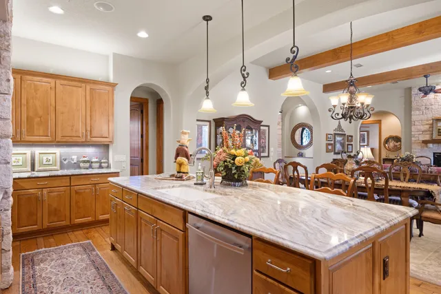 a kitchen with stainless steel appliances granite countertop a sink a stove and a wooden floors