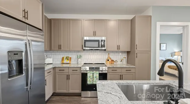 a kitchen with stainless steel appliances granite countertop a stove a sink and a microwave