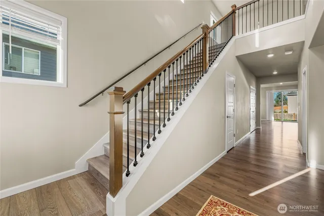 a view of staircase with lots of frames on wall and wooden floor