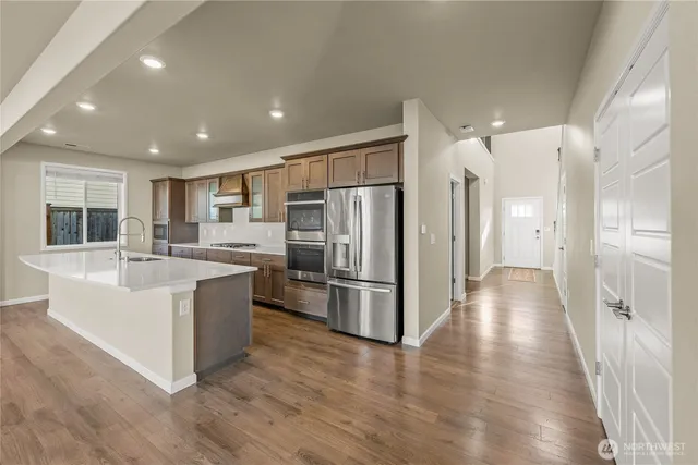 a large white kitchen with stainless steel appliances granite countertop a refrigerator and a sink