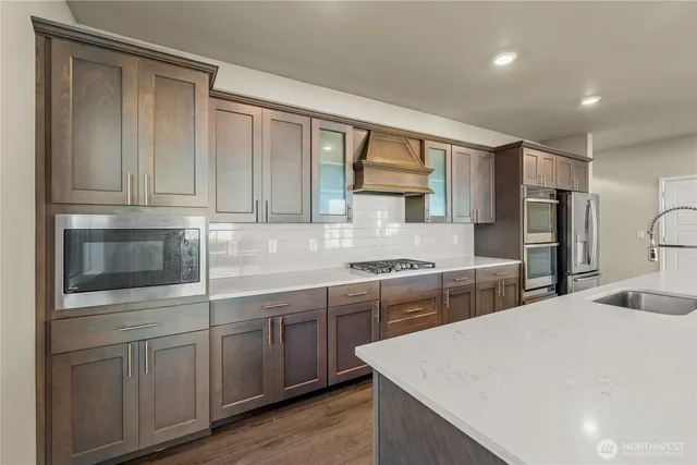 a kitchen with stainless steel appliances granite countertop a sink and cabinets with wooden floor