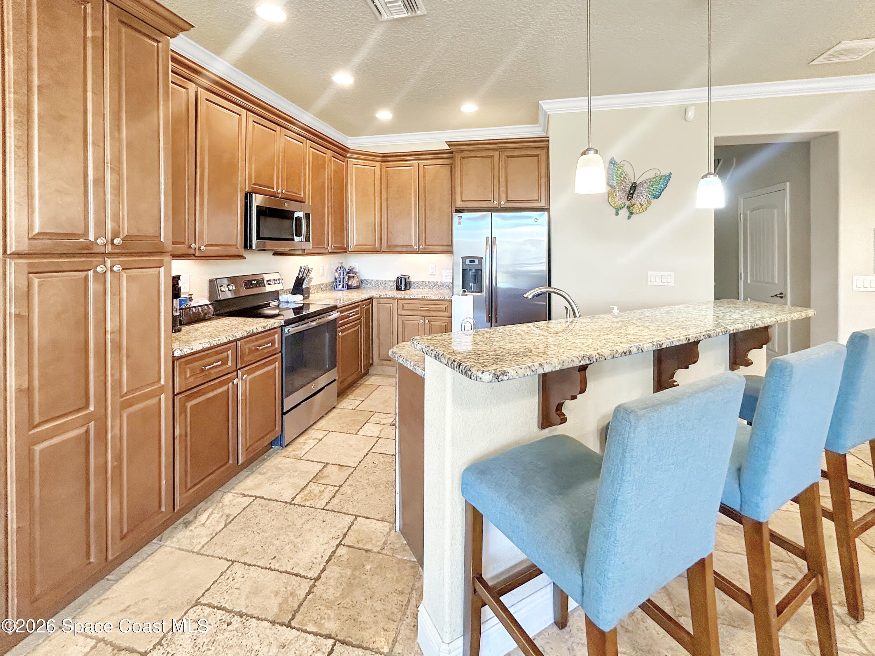 2709 Cutlass Point Lane, Unit 103 Merritt Island, FL 32953 - Photo 8 of 31 a open kitchen with stainless steel appliances kitchen island granite countertop a sink dishwasher a stove a refrigerator with a dining table and chairs