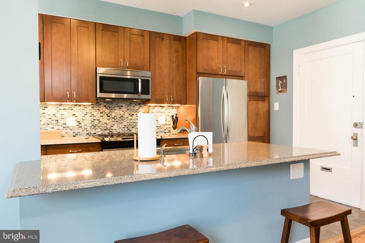 1734 P Street Northwest, Unit 46 Washington, DC 20036 - Photo 12 of 16 a kitchen with stainless steel appliances a microwave a stove and white cabinets