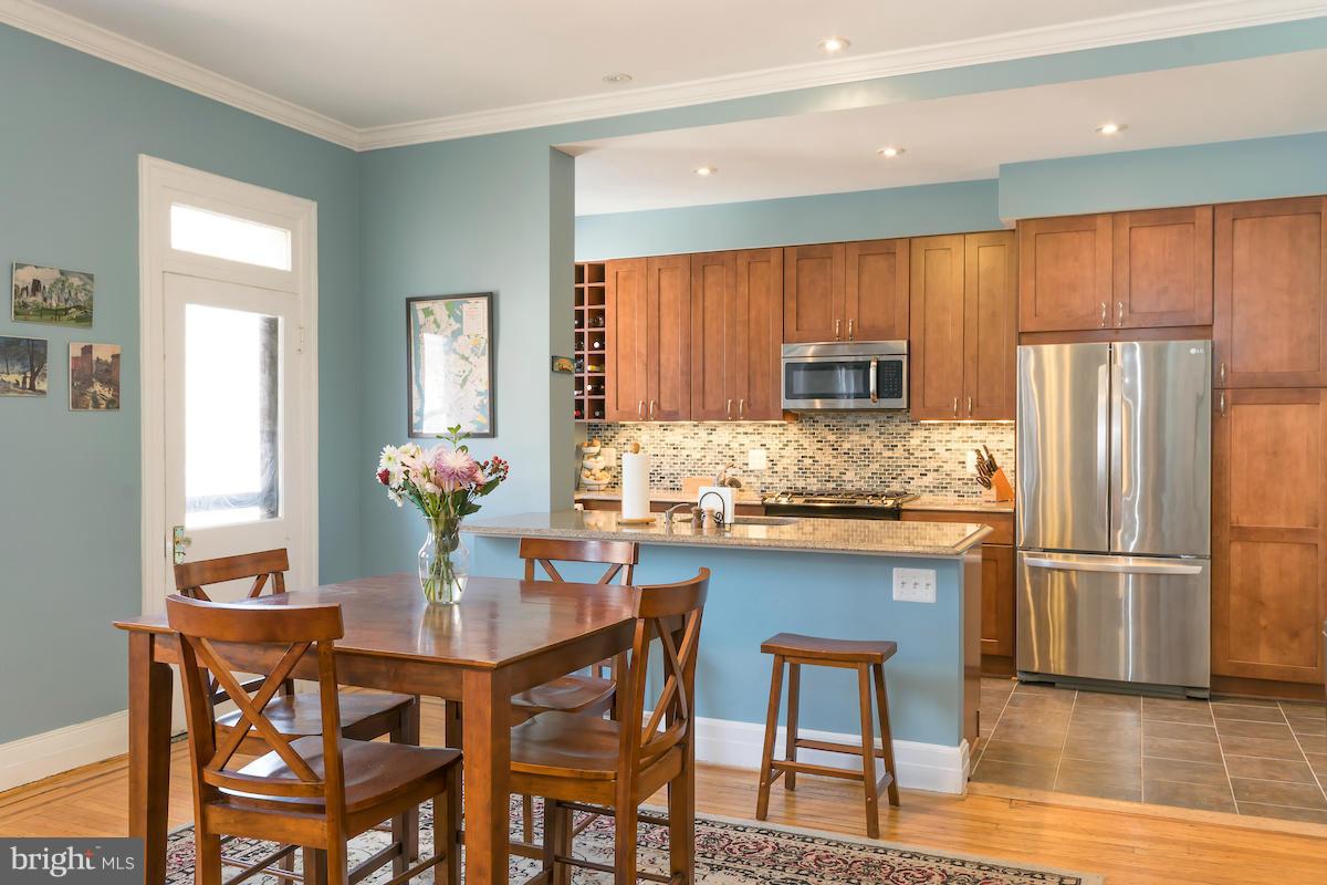 1734 P Street Northwest, Unit 46 Washington, DC 20036 - Photo 8 of 16 a kitchen with granite countertop wooden floor cabinets dining table and stainless steel appliances