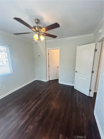 a view of an empty room with wooden floor and a ceiling fan