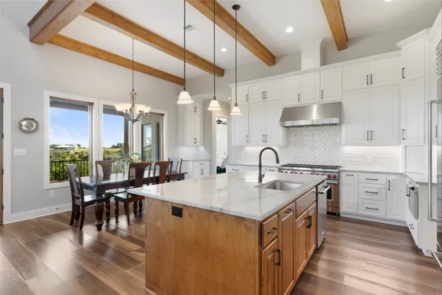a kitchen with stainless steel appliances granite countertop a sink a stove and a wooden floors
