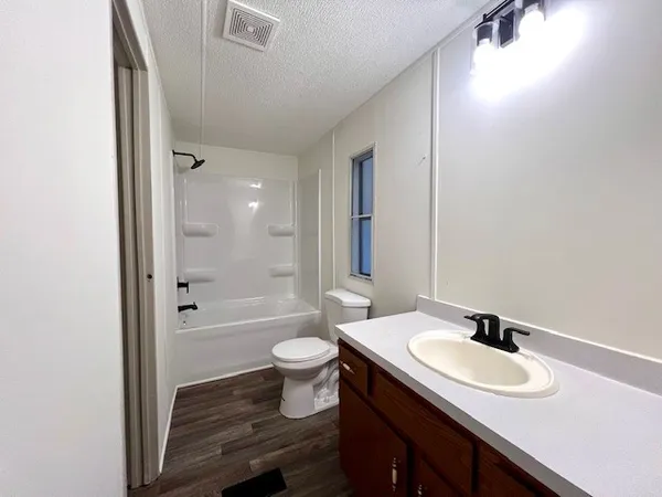 a bathroom with a granite countertop sink toilet a mirror and shower