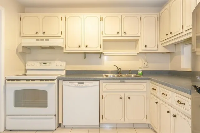 a kitchen with granite countertop white cabinets and white appliances