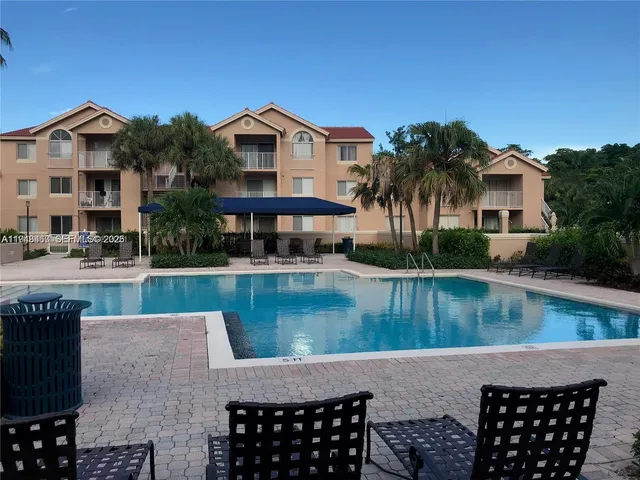 a view of a patio with couches table and chairs with swimming pool and barbeque oven
