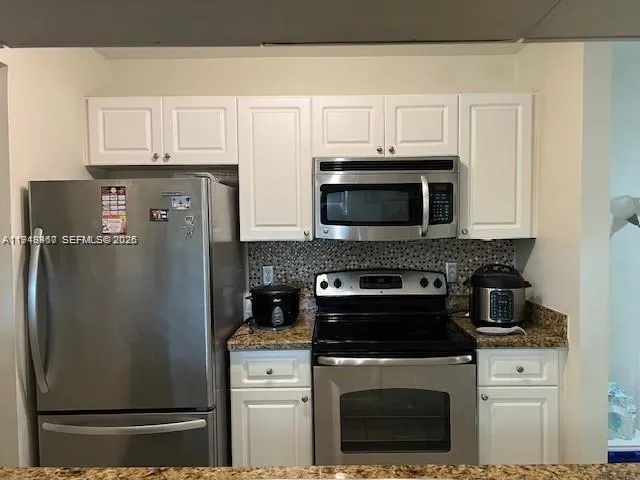 a kitchen with stainless steel appliances granite countertop a refrigerator stove and microwave