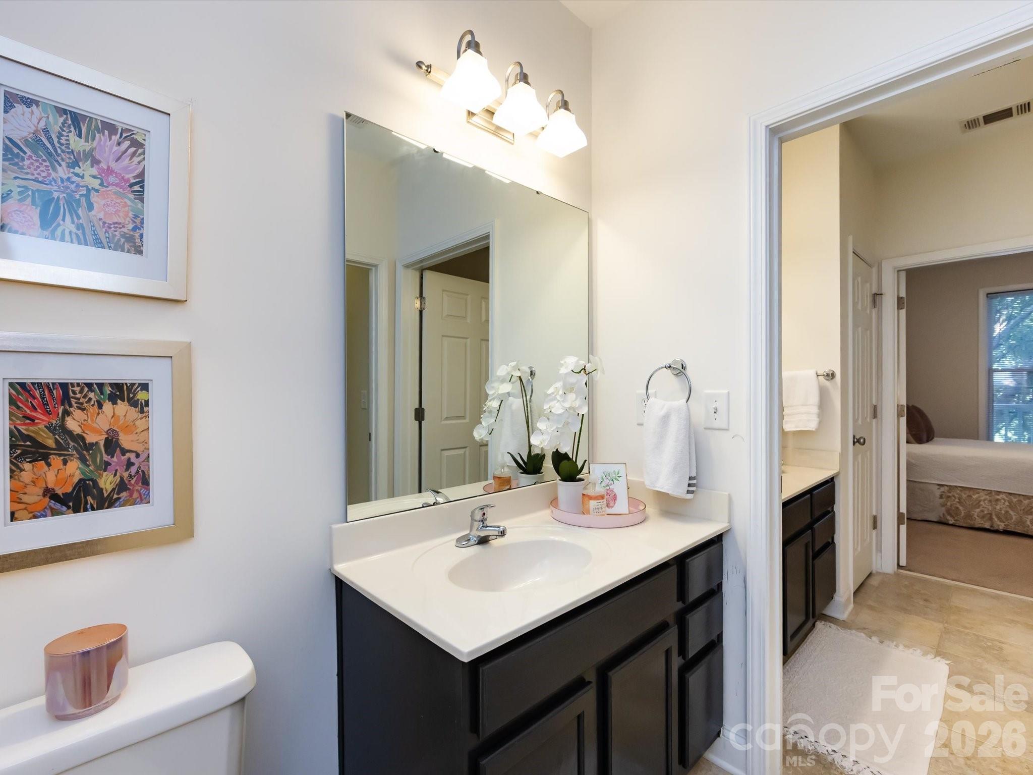 1000 East Woodlawn Road, Unit 113 Charlotte, NC 28209 - Photo 25 of 32 a bathroom with a sink a toilet and a mirror