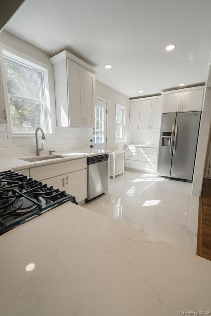 29 Avon Road Hewlett, NY 11557 - Photo 6 of 17 Kitchen with white cabinetry, light marble finish floors, backsplash, appliances with stainless steel finishes, and recessed lighting
