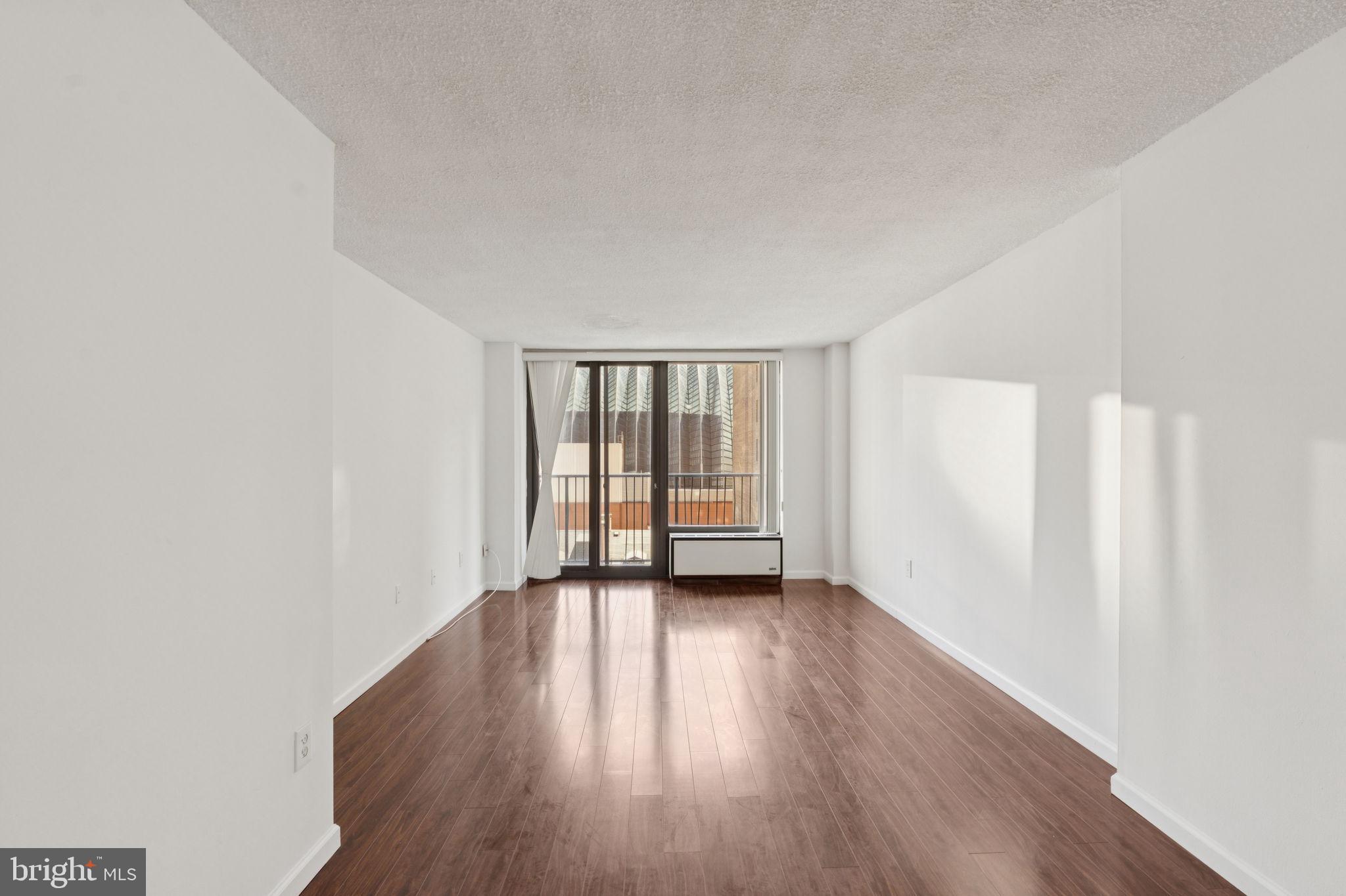 1420 Locust Street, Unit 7L Philadelphia, PA 19102 - Photo 2 of 25 a view of an empty room with wooden floor and a window