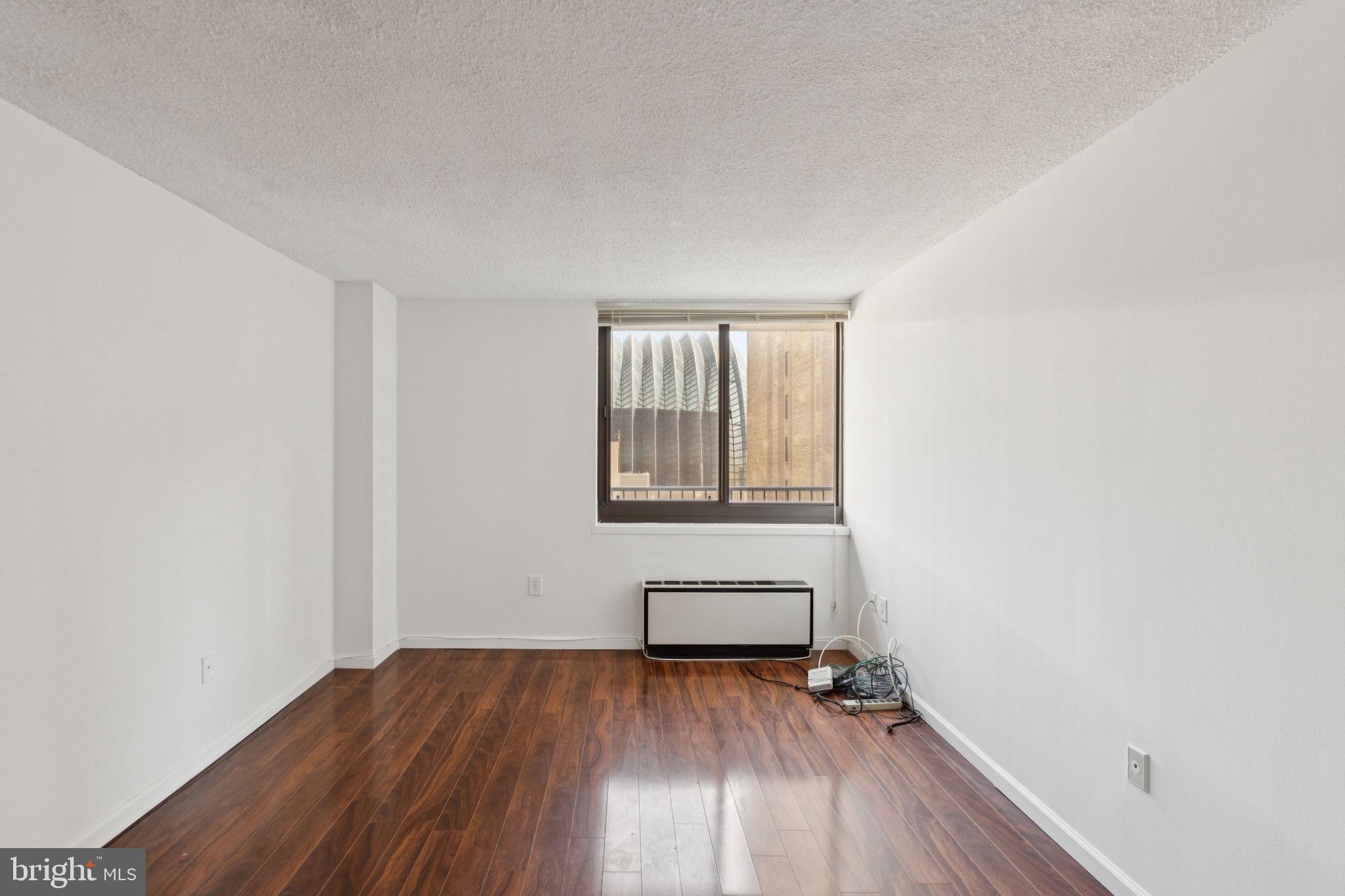 1420 Locust Street, Unit 7L Philadelphia, PA 19102 - Photo 9 of 25 a view of an empty room with wooden floor and a window
