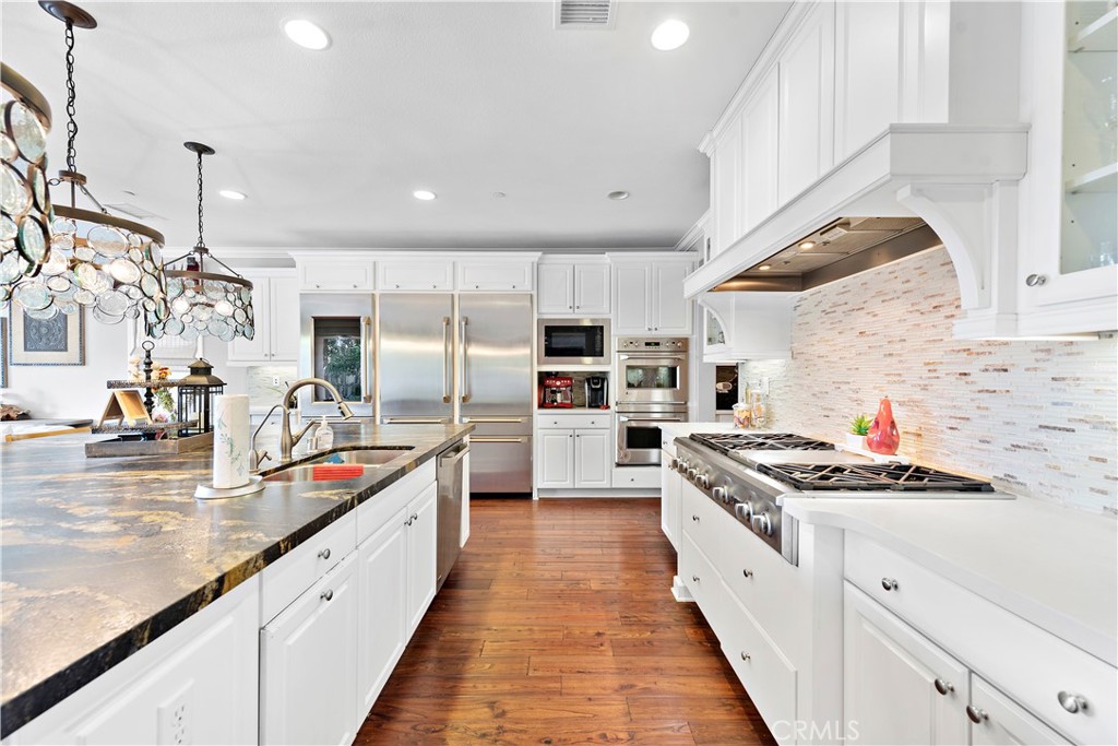 108 Fairgrove Irvine, CA 92618 - Photo 5 of 40 a kitchen with stainless steel appliances kitchen island granite countertop a sink a stove and a wooden floors