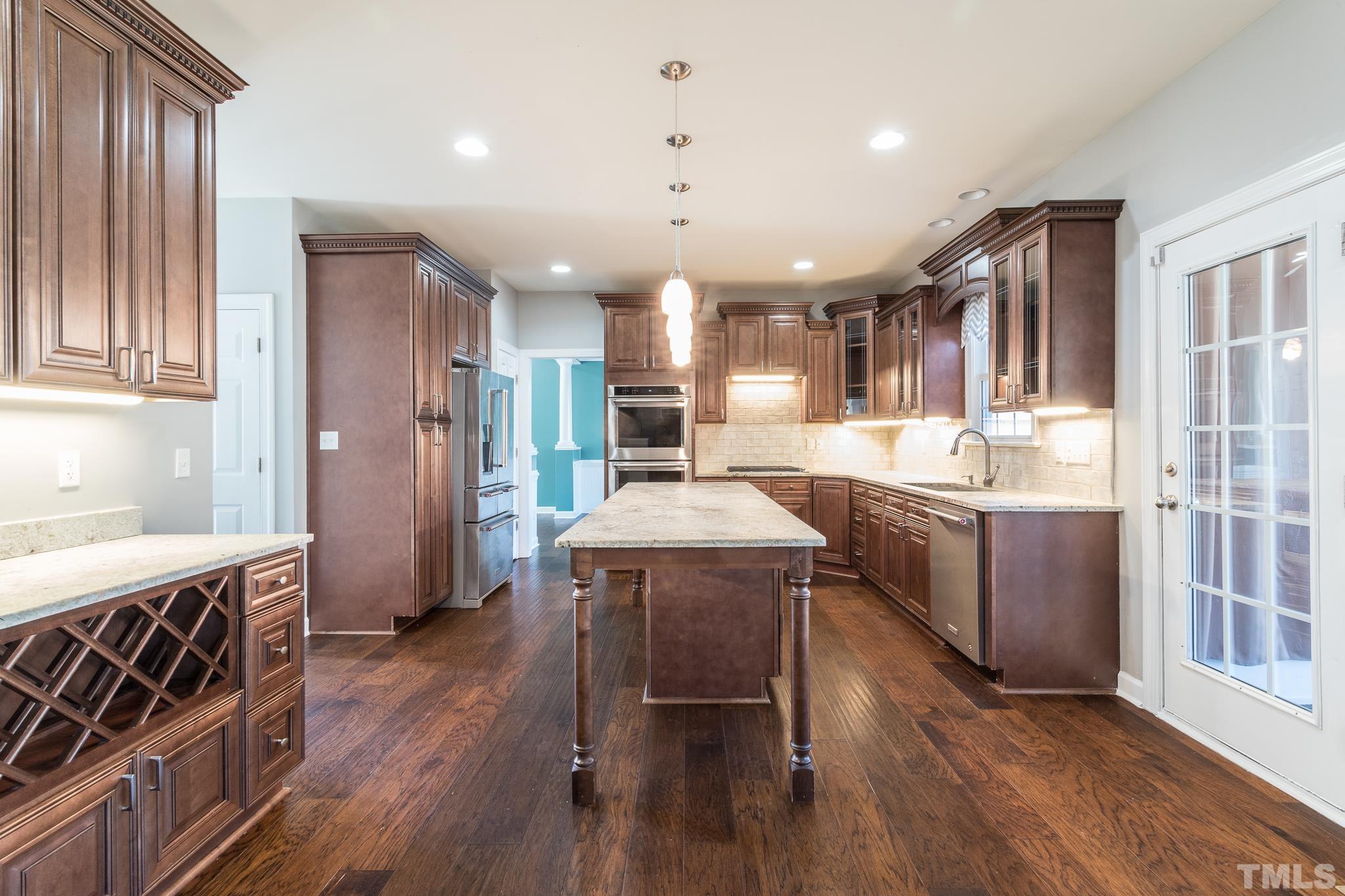 6023 Clapton Drive Wake Forest, NC 27587 - Photo 11 of 35 a kitchen with kitchen island granite countertop wooden floors and stainless steel appliances