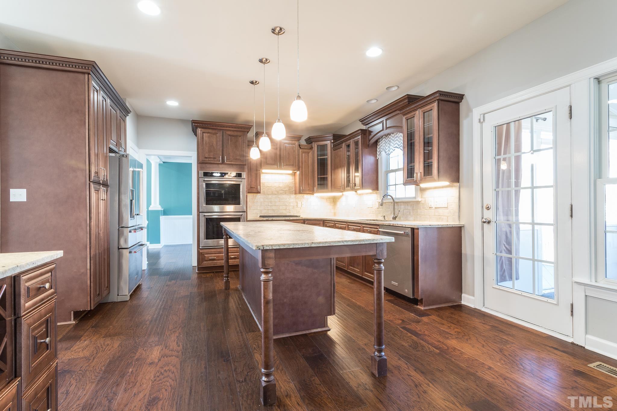 6023 Clapton Drive Wake Forest, NC 27587 - Photo 8 of 35 a kitchen with stainless steel appliances granite countertop a refrigerator a sink dishwasher a stove and a dining table with wooden floor