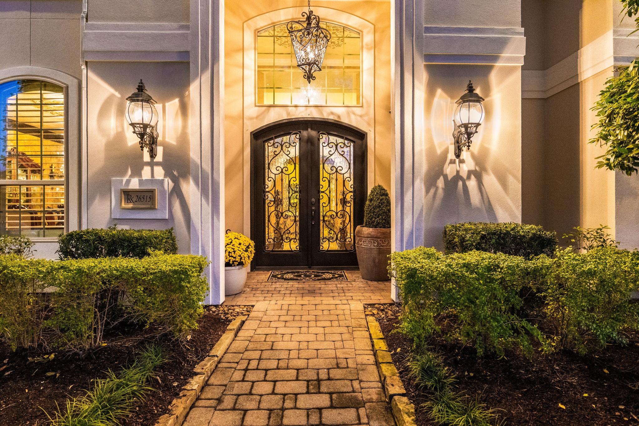 26515 Ashley Ridge Lane Katy, TX 77494 - Photo 4 of 50 The stunning entryway with beautiful wrought-iron double doors, accent lighting that highlights the architectural details, and a pave stone walkway framed by manicured hedges.