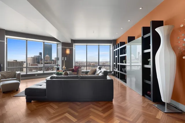 a living room with furniture floor to ceiling window and kitchen view