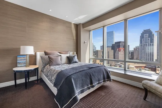 a spacious bedroom with a bed a lamp and a large window