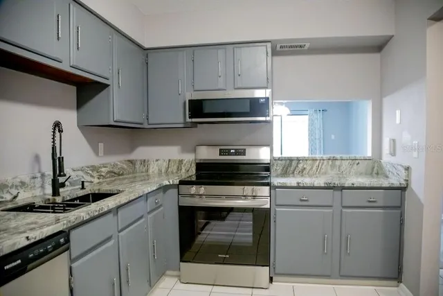 a kitchen with granite countertop a stove sink and cabinets